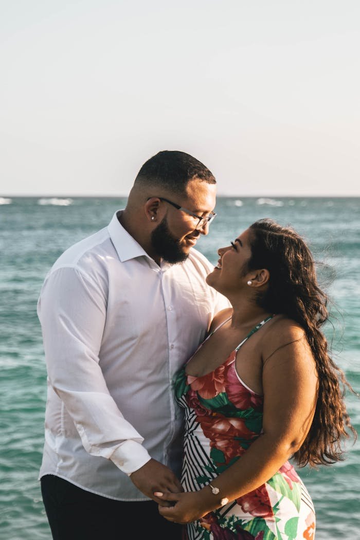 A couple shares a romantic moment by the turquoise sea in Aruba, showcasing love and togetherness.